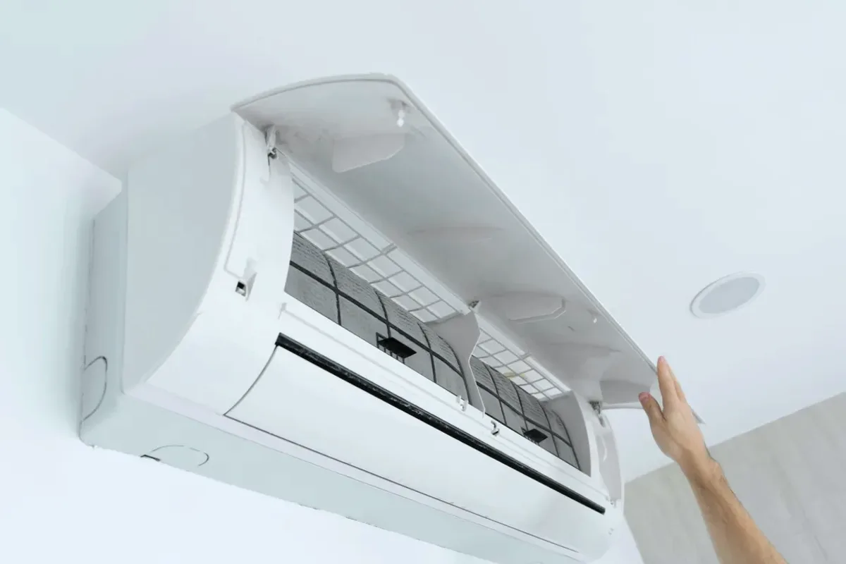 Hand opening the cover of a wall-mounted ductless air conditioner